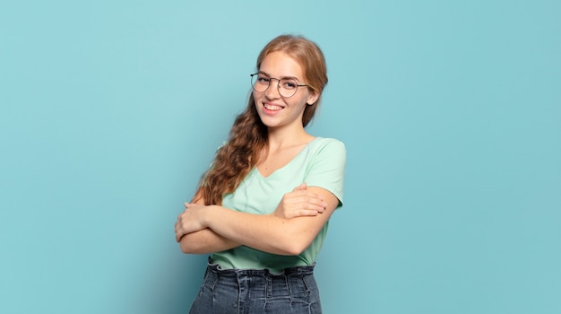 Donna graziosa bionda che ride felice con le braccia incrociate, con una posa rilassata, positiva e soddisfatta