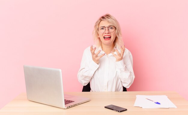 Donna graziosa bionda giovane donna graziosa che sembra disperata, frustrata e stressata. concetto di scrivania dell'area di lavoro