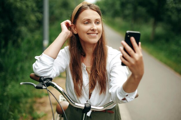 Donna graziosa che fa selfie sullo smartphone durante il giro in bicicletta