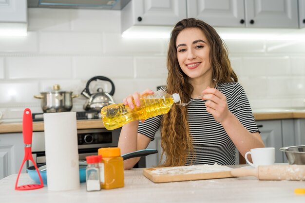 Donna graziosa che impasta la pasta a casa, cucina il cibo per uno stile di vita sano