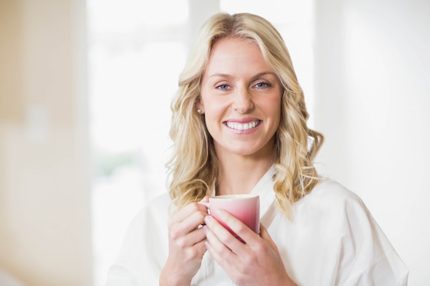 Donna graziosa che mangia una tazza di caffè nella cucina