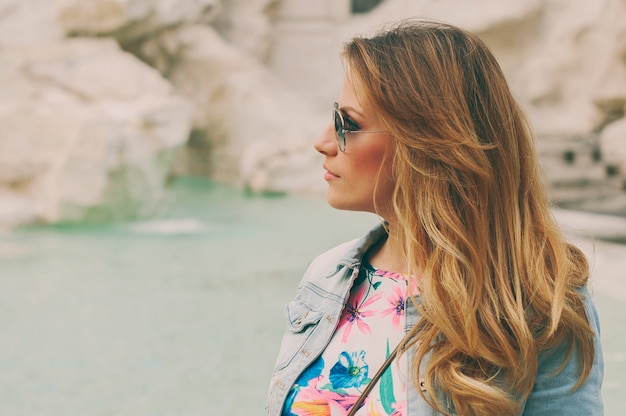 Donna graziosa che osserva alla fontana di Trevi durante il suo viaggio a Roma