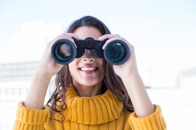 Donna graziosa che osserva tramite il binocolo