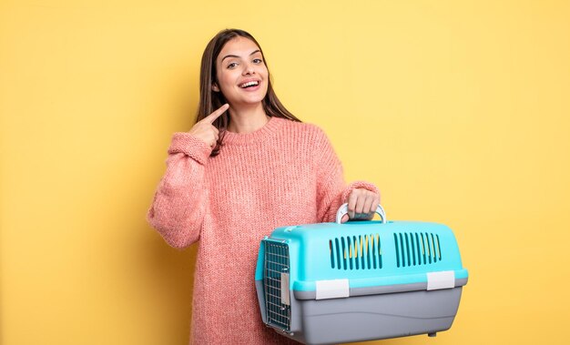 Donna graziosa che sorride con sicurezza indicando il proprio concetto di trasportino per animali domestici con ampio sorriso