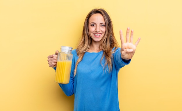 Donna graziosa che sorride e che sembra amichevole che mostra il concetto di succo d'arancia numero quattro