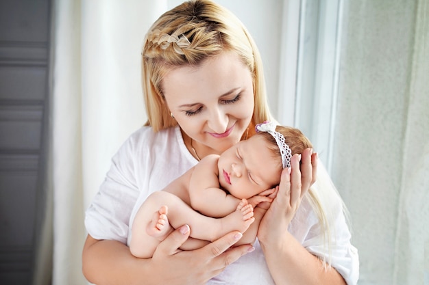 Donna graziosa che tiene una neonata in braccio. Madre felice e il suo bambino appena nato scivoloso. Concetto di famiglia felice