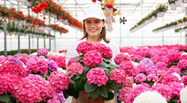 Donna graziosa che tiene vaso con fiori rosa