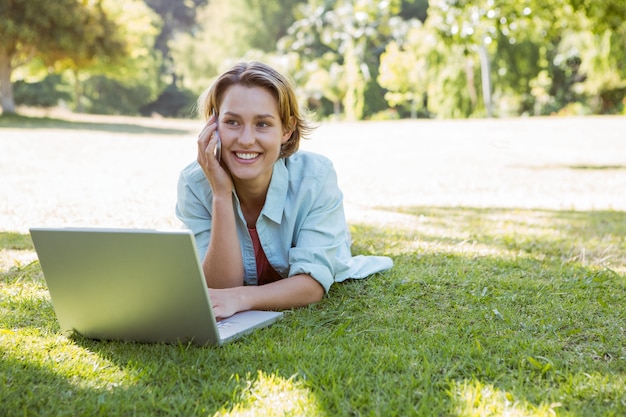 Donna graziosa che utilizza computer portatile nel parco