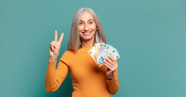 Donna graziosa dei capelli grigi con le banconote