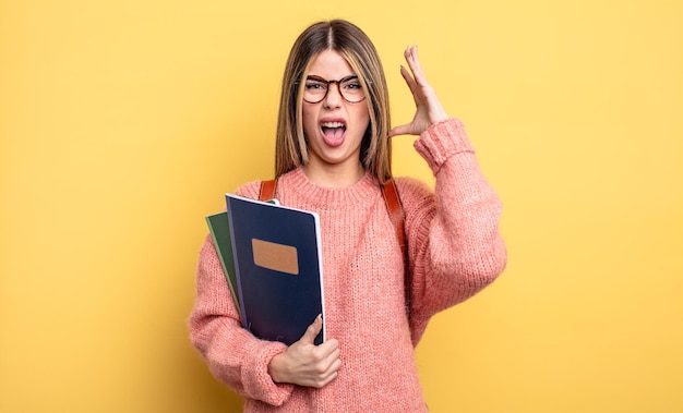 Donna graziosa dell'allievo che grida con le mani in alto. libri e zaino