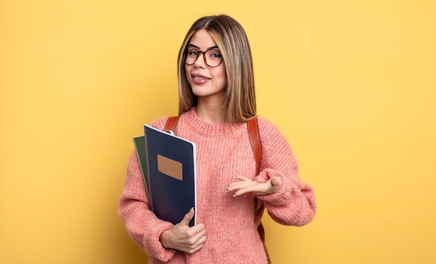 Donna graziosa dello studente che sorride allegramente sentendosi felice e mostrando un concetto libri e zaino