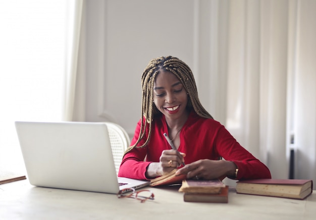 Donna graziosa di afro che lavora ad uno scrittorio