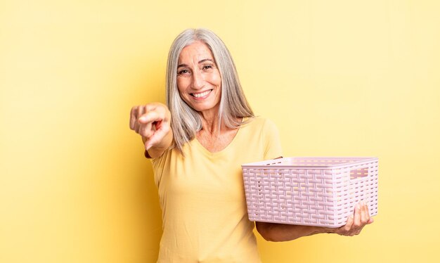 donna graziosa di mezza età che punta alla telecamera scegliendo te. concetto di cestino vuoto