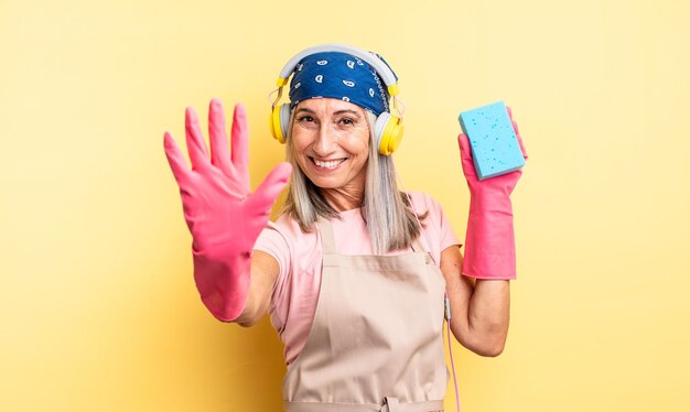 Donna graziosa di mezza età che sorride e che sembra amichevole mostrando il numero cinque del pulitore abrasivo