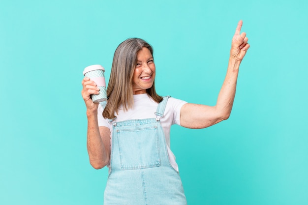 Donna graziosa di mezza età che tiene un caffè da asporto?