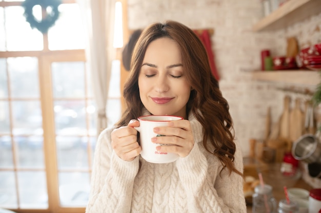 Donna graziosa felice che gode del suo tè del mattino