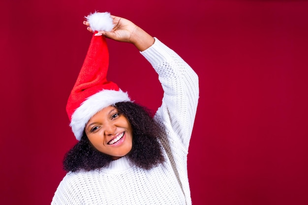 Donna graziosa gioiosa in cappello rosso di Babbo Natale che ride isolata su sfondo rosso è felice ed eccitata piena di divertimento