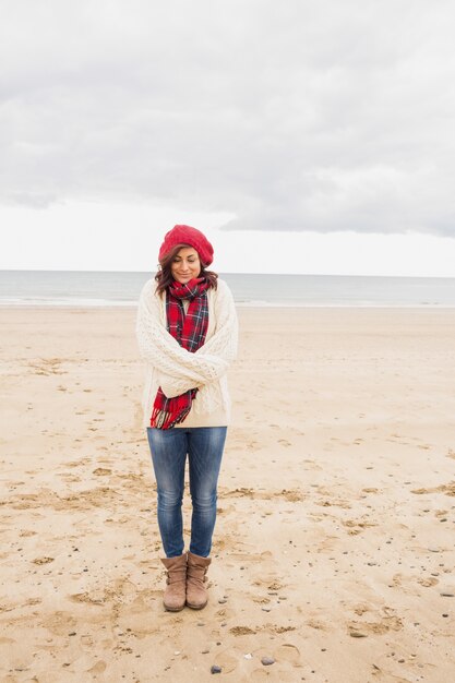 Donna graziosa in vestiti caldi alla moda in spiaggia