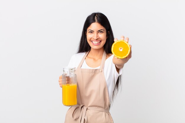 Donna graziosa ispanica del cuoco unico. succo d'arancia e concetto di colazione