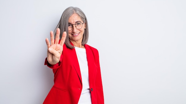 Donna graziosa senior che sorride e che sembra amichevole, mostrando il numero quattro. concetto di donna d'affari