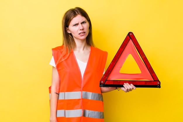 Donna graziosa testa rossa che si sente perplessa e confusa pericolo del triangre dell'auto