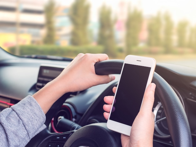Donna guida e utilizzando smartphone sulla strada