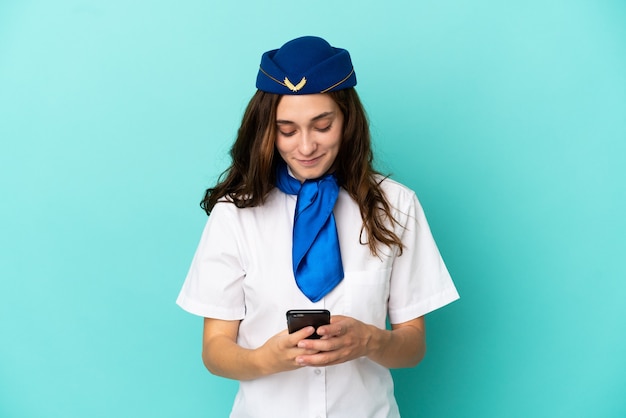 Donna hostess aereo isolata su sfondo blu che invia un messaggio con il cellulare