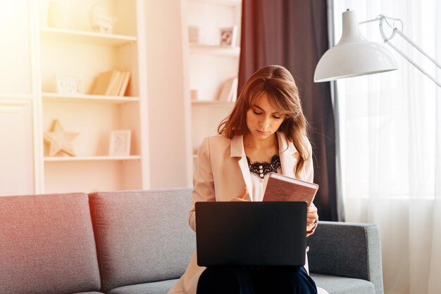 Donna imprenditrice che lavora con un computer portatile seduto su un divano a casa