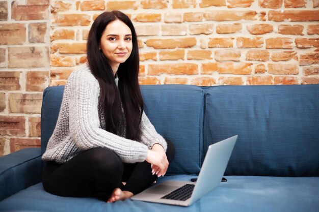 Donna in abbigliamento casual che utilizza laptop e sorride mentre lavora in casa.