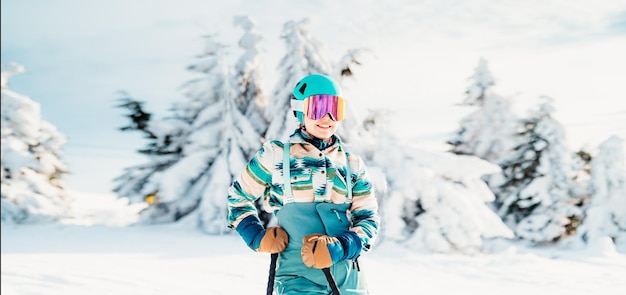 Donna in abbigliamento da sci con casco e occhiali da sci in testa con bastoncini da sci Tempo invernale sulle piste In cima a una montagna e vista panoramica Sciatore alpino Sport invernali
