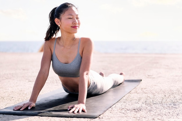 Donna in abbigliamento sportivo che fa yoga sul mare