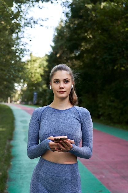 Donna in abbigliamento sportivo in pista con un telefono cellulare