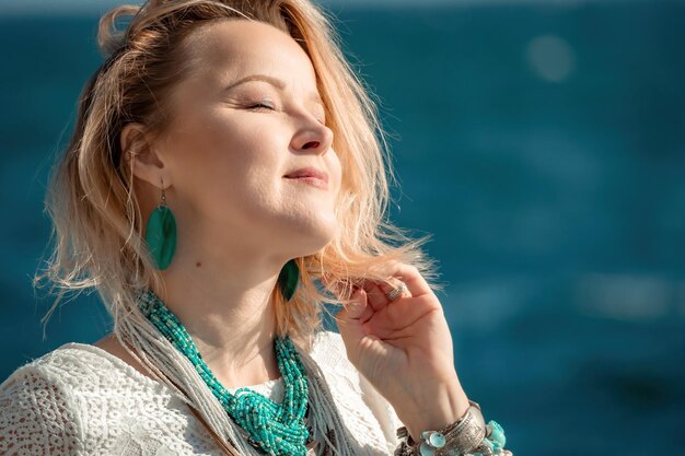 Donna in abiti bohémien sulla spiaggia al tramonto in stile boho per un look alla moda sul resort di mezza età