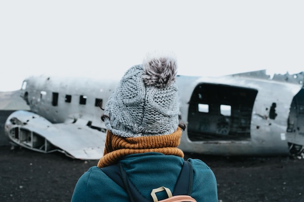 Donna in abiti invernali di fronte al relitto dell'aereo precipitato in Islanda sulla spiaggia di Solheimasandur Viaggio in Islanda concetto di viaggio su strada Copia spazio immagine visita Islanda