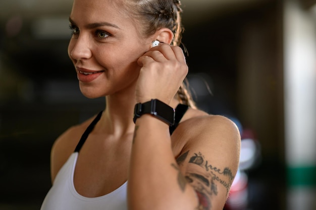 Donna in abiti sportivi che si mette gli airpod nelle orecchie prima dell'allenamento