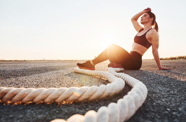 Donna in abiti sportivi che si siede con i nodi sulla strada alla sera