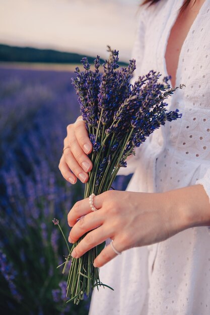 Donna in abito bianco con bouquet di fiori di lavanda