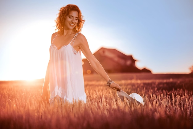 Donna in abito bianco in piedi in un campo di grano