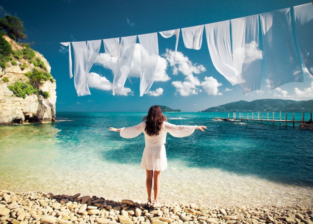 donna in abito bianco in piedi sulla spiaggia