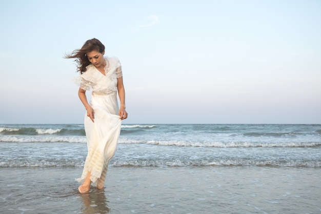 Donna in abito bianco sulla spiaggia