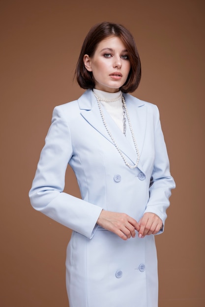Donna in abito blu nello stile di un'assistente di volo hostess su sfondo marrone Taglio di capelli Bob
