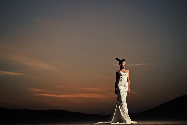 Donna in abito da sposa bianco al tramonto