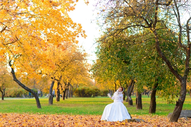 Donna in abito da sposa bianco lungo in un parco