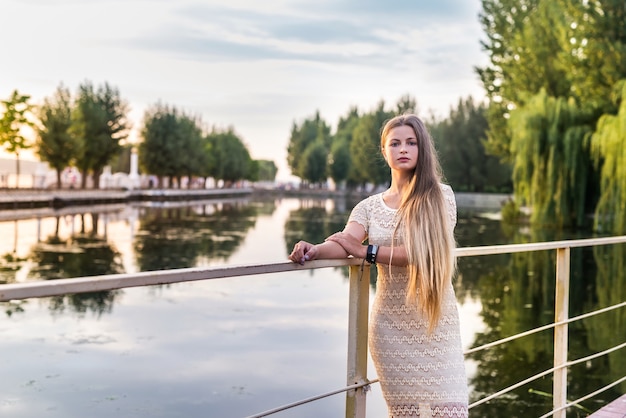 Donna in abito elegante in posa sul molo sul lago