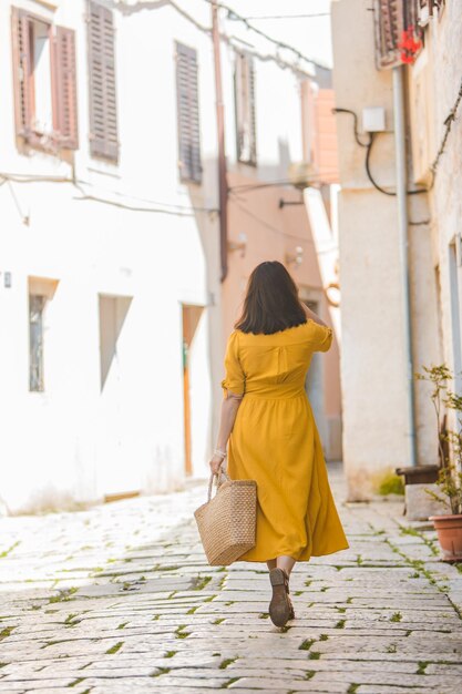 Donna in abito giallo con cappello di paglia a piedi dalla vecchia città turistica di porec in croazia