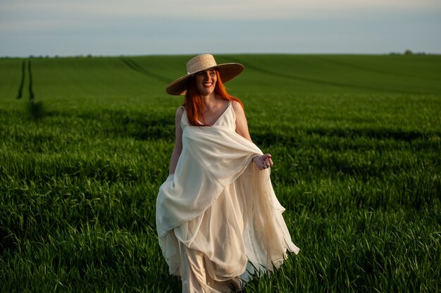 Donna in abito lungo bianco all'aperto in campo verde