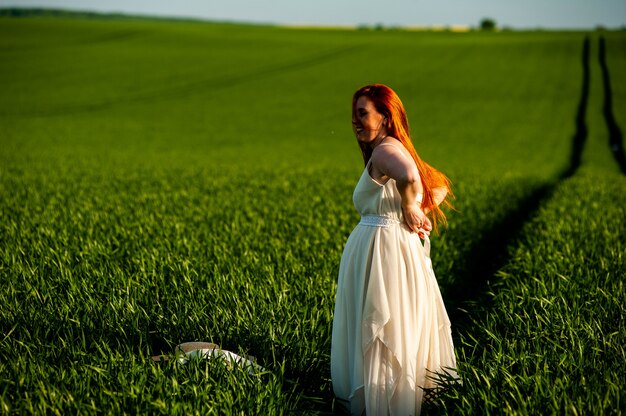 Donna in abito lungo bianco su un campo verde