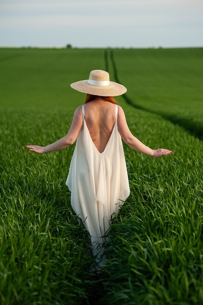 Donna in abito lungo bianco su un campo verde