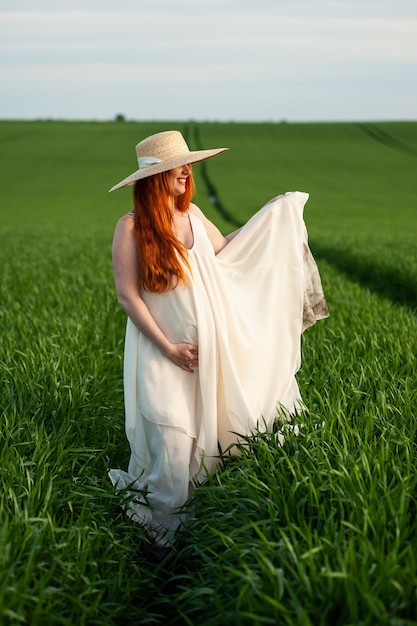 Donna in abito lungo bianco su un campo verde