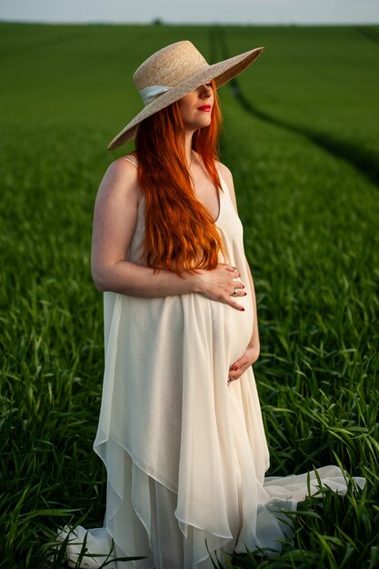 Donna in abito lungo bianco su un campo verde